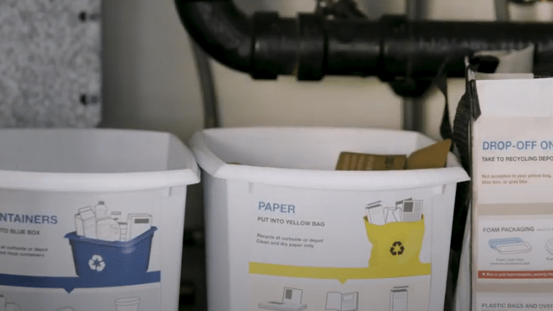 Recycling bins under a kitchen sink labeled with Recycle BC material categories