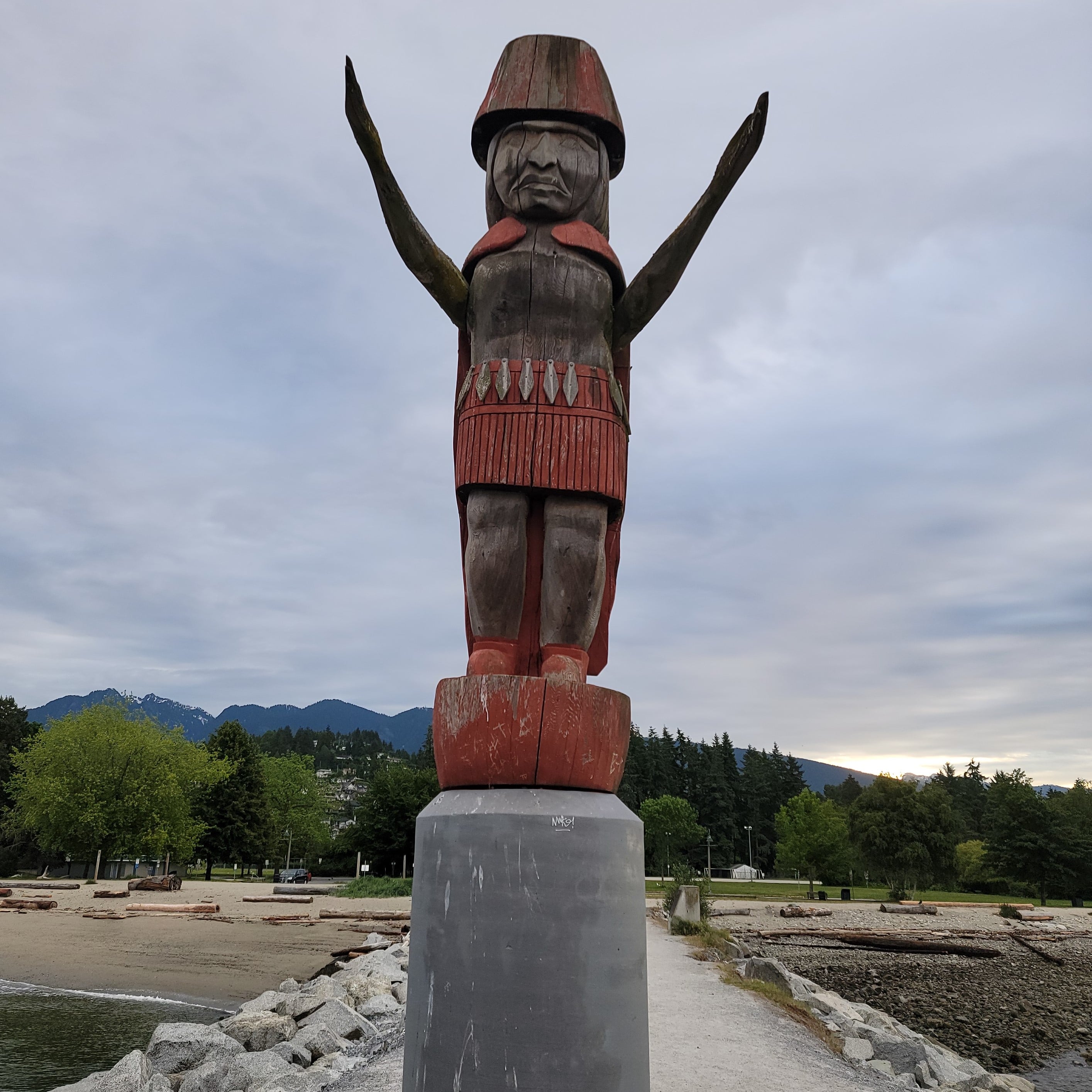 Welcoming Figure wood carving with arms raised on the shores of Squamish Nation